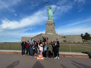 Students and facilitators pose for a picture in front of the Statue of Liberty