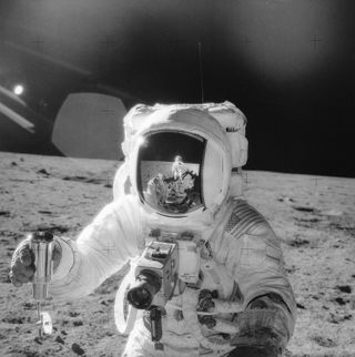 An Apollo 12 astronaut at work collecting a moon rook from the lunar surface.