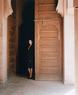 Model wears black against backdrop of Moroccan hotel