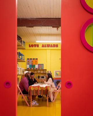 Yinka Ilori and colleagues laughing at table in the designer's colourful London studio