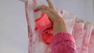 A shower curtain being cleaned with a pink cloth