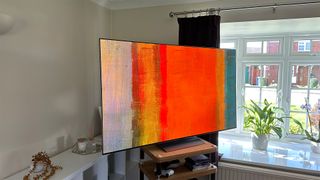 LG OLED65G3 on a TV stand with orange artwork on the screen