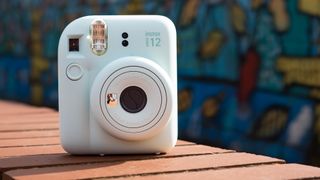 Instax Mini 12 on a brick wall in front of graffiti