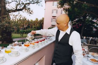 waiter pours tea in hotel garden