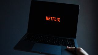 Netflix on a laptop being held in the air