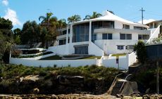 A large white mansion with a glass front and exterior wall. 