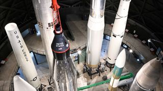 a large white and silver rocket stands upright in a large hangar