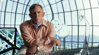 Daniel Craigin Benoit Blanc katsoo tutkivasti eteenpäin Knives Out 2 -elokuvan lasirakennuksessa