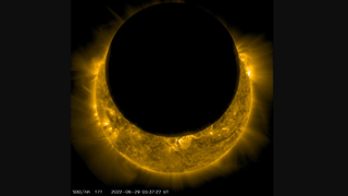 The dark circle of the moon occults part of the sun.