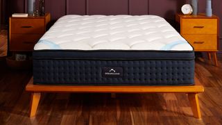 The DreamCloud Premier Hybrid Mattress on a wooden bedframe