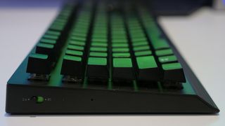 Razer BlackWidow V3 Pro side view flat with green lighting from monitor