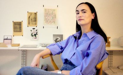 Frida Escobedo sitting in a wooden chair in front of her desk.the architect won the 2024 Charlotte Perriand award