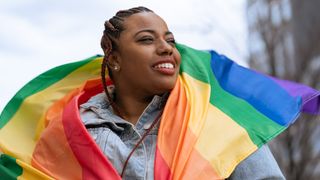 smiling person wearing a pride flag draped over their shoulders