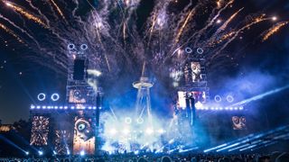 a large stage with various lights and fireworks exploding overhead.