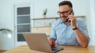 A man talking on his phone while on a laptop