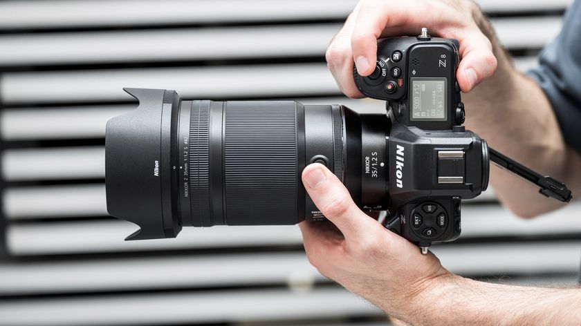 Nikon Z 35mm f/1.2 S in the hand in front of gray slatted backdrop