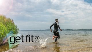 Person running into lake wearing wetsuit