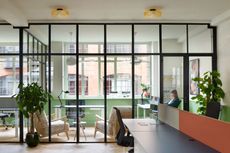 drama republic offices, looking through glazed partition into desk with woman typing