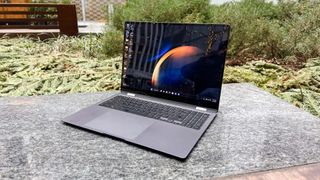 A laptop sitting on a backyard table with plants in the background.