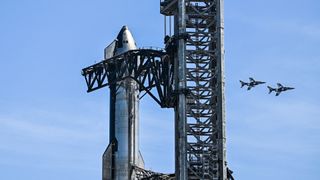 a large silver rocket flies through a blue sky above a column of flame