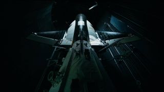 close up view, from behind, of a black and white space plane in a dark room