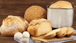 A selection of bread next to a loaf in a bread machine pan