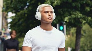 Man wearing JBL Live 770NC headphones on street.