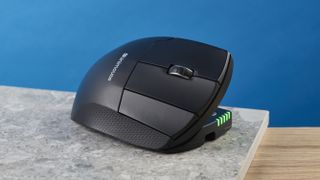 A photo of the Contour Unimouse on a stone surface and a wooden desk, all set against a dark blue background.