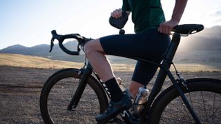 a photo of a cyclist using a Theragun Mini on the bike