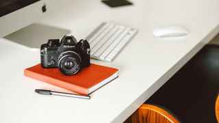 Camera on notepad, on desk in front of Mac