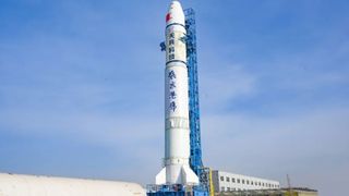 a white rocket stands upright on a launch pad