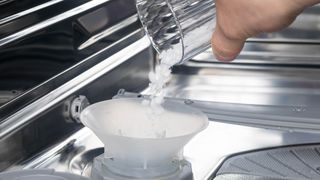 Dishwasher salt being added to the salt reservoir in a dishwasher