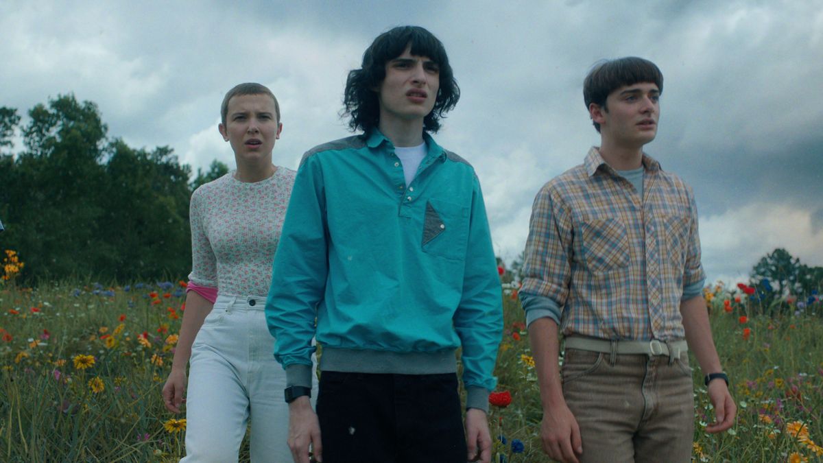 Eleven, Mike, and Will (L-R) stand in a field in &quot;Stranger Things&quot; season 4 