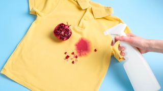Spraying pomegranate stain on yellow t shirt