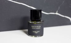 View of James Heeley’s Phoenicia fragrance on a white surface pictured against a grey background with a white cracked effect