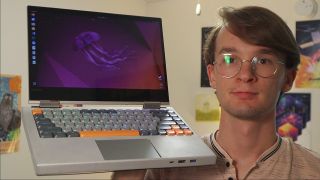 Marcin Plaza holding a Lenovo Yoga laptop with a custom titanium case and a mechanical keyboard