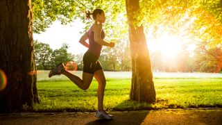 a woman running through the park on a very sunny day