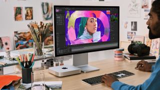 Mac mini M2 on a desk being used by a model, in promo image provided by Apple