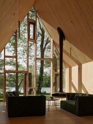 the lake house, a timber structure in a forest, made up of a cluster of volumes with pitched roofs