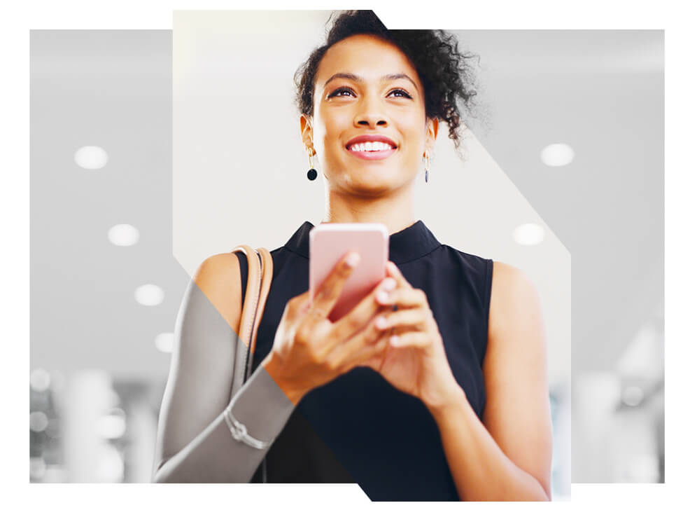 Woman with mobile device in hand and smiling
