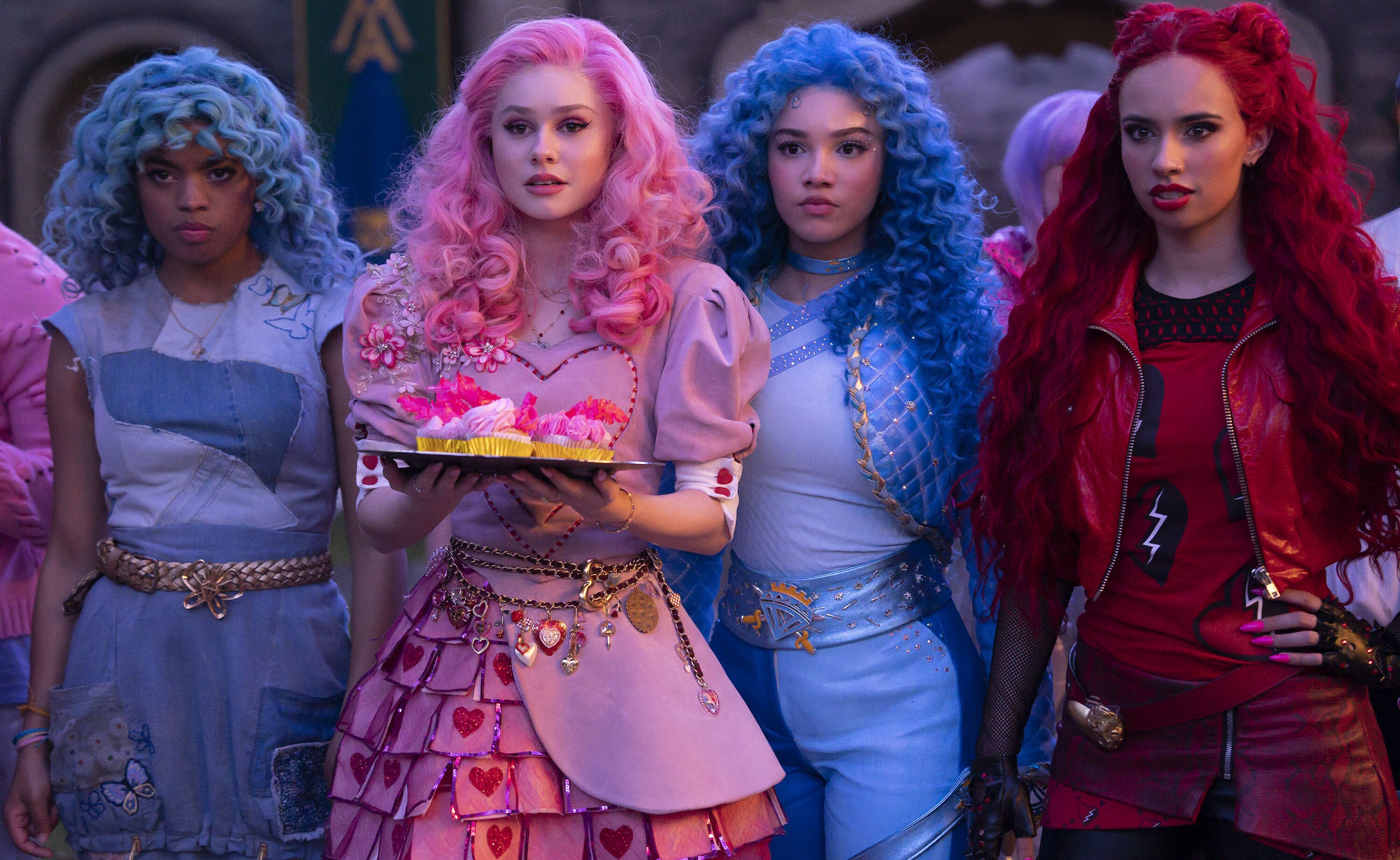 A group of girls in very brightly colored wigs, one in pale blue, one in bubblegum pink, another in a slightly darker blue, and one in red.