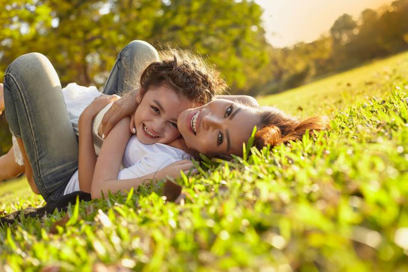 Madre e hijo jugando en el jardín, abrazándose y sonriendo