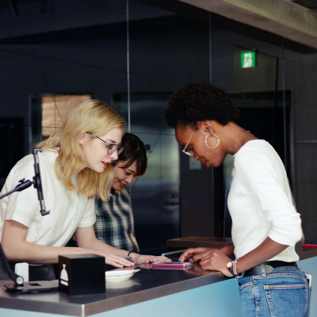 Due donne alla reception che aiutano un ospite a fare il check-in