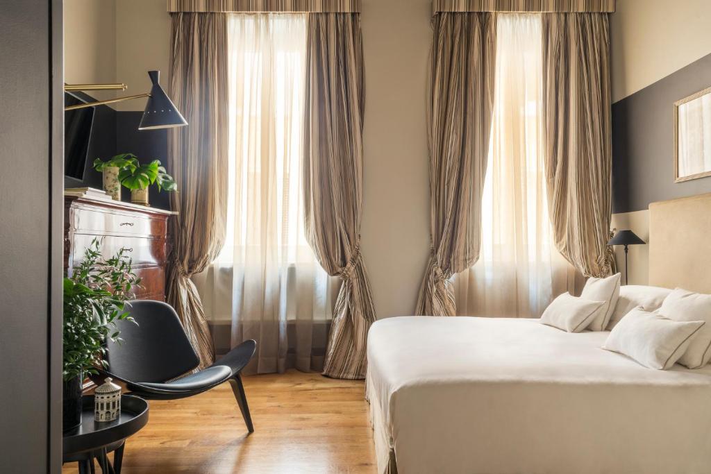 a bedroom with a bed and a chair and a window at Crossing Condotti in Rome