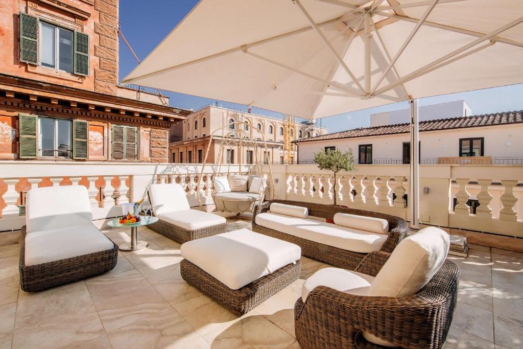 a patio with white furniture and an umbrella at Aleph Rome Hotel, Curio Collection By Hilton in Rome