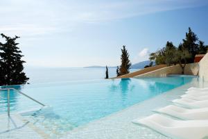 einen Pool mit Stühlen und Blick auf das Wasser in der Unterkunft Nido, Mar-Bella Collection in Agios Ioannis Peristerion