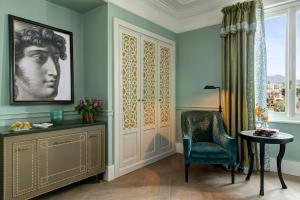 a room with a chair and a table and a window at Rocco Forte Hotel De La Ville in Rome