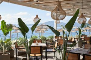 ein Restaurant mit Tischen und Stühlen und Meerblick in der Unterkunft MarBella, Mar-Bella Collection in Agios Ioannis Peristerion