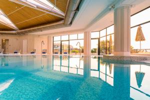 a swimming pool in a hotel with glass windows at Grand Palladium Sicilia Resort & Spa in Campofelice di Roccella