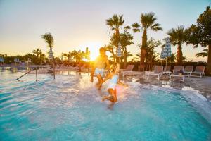 een man en een vrouw spelen in een zwembad bij Grand Palladium Sicilia Resort & Spa in Campofelice di Roccella